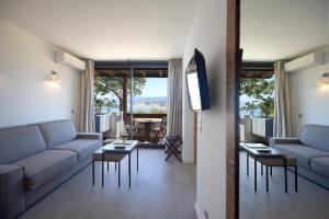a living room with couches and tables and a television at Hôtel La Roya in Saint-Florent