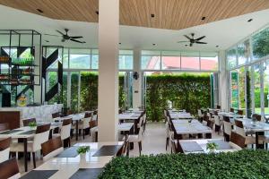 un restaurante con mesas, sillas y ventanas en The Palmery Resort - SHA Extra Plus en Kata