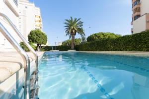 una piscina en un edificio con una palmera en Acapulco IV, en Gandía
