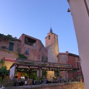 um edifício com uma torre de relógio ao fundo em Maison d'hôtes Une hirondelle en Provence em Roussillon