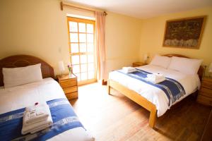 a bedroom with two beds and a window at Apu Lodge in Ollantaytambo