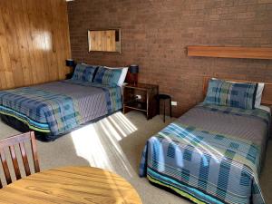 een kamer met twee bedden en een tafel erin bij Kingswood Motel in Tocumwal