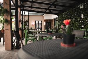 a patio with tables and green chairs and plants at The One Surat in Suratthani