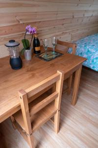 a wooden table with two glasses and flowers on it at The Moat Lake Glamping Pod in Clare