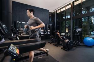 un homme qui court sur un tapis de course dans une salle de sport dans l'établissement Village Hotel Sentosa by Far East Hospitality, à Singapour