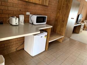a kitchen with a microwave and a refrigerator at Kingswood Motel in Tocumwal
