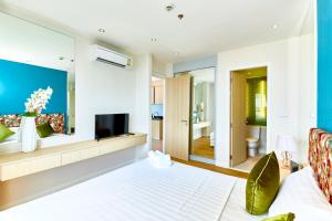 Grande Carribean sea view apartments Jomtien beach في جنوب باتايا: غرفة معيشة فيها سرير وتلفزيون