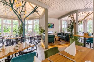 a restaurant with tables and chairs and windows at Parkhotel Diani in Leipzig