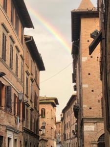 un arcobaleno nel cielo sopra un vicolo con edifici di Salicotto 56 a Siena