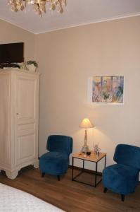 salon z 2 niebieskimi krzesłami i stołem w obiekcie B&B LES CRESSES w mieście Ciney