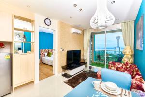 a living room with a blue couch and a television at Grande Carribean sea view apartments Jomtien beach in Pattaya South