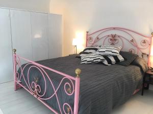 Una cama rosa con almohadas blancas y negras. en a casa del reuccio, en Catania