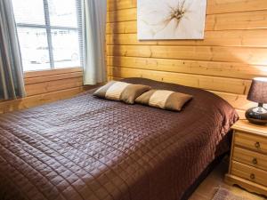 een slaapkamer met een bed met een houten muur bij Holiday Home Aaria by Interhome in Tahkovuori +8 foto's