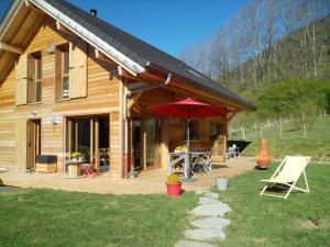 une cabane en bois avec un parasol et des chaises rouges dans l'établissement La Buissonnière, à Le Noyer