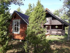 a log cabin in the woods with a tree at Pähkli Seaside Cottage with Cozy Outdoor Patio in Kõiguste