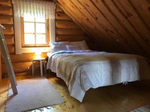 um quarto com uma cama num chalé de madeira em Pähkli Seaside Cottage with Cozy Outdoor Patio em Kõiguste