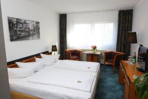 
a hotel room with two beds and a desk at Airport Hotel Erfurt in Erfurt
