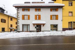 un edificio bianco con la neve davanti di Locanda Farinati ad Abetone