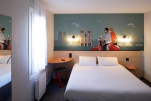 ラ・シャペル・サン・メマンにあるKYRIAD DIRECT Orleans - La Chapelle St Mesminのベッド付きの客室で、壁には絵画が飾られています。