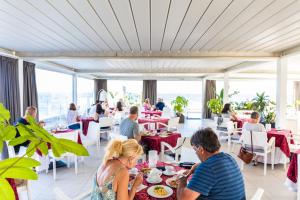 un groupe de personnes assises à table dans un restaurant dans l'établissement Victoria Palace Cefalù, à Cefalù