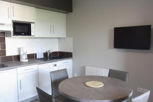 cocina con mesa y algunas sillas y TV en Résidence Le 101, en Millau 14 fotos más