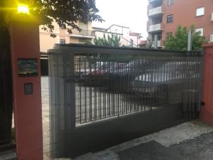 a gate to a parking lot with cars behind it at Casa Soave B&B in Alba