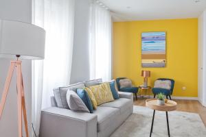 a living room with a couch and a yellow wall at Canaan Boutique Apartments Madrid in Madrid