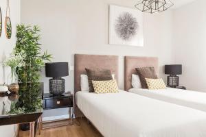 two beds in a white room with plants and lamps at Canaan Boutique Apartments Madrid in Madrid