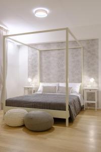 una camera bianca con un letto a baldacchino con due tavoli di Bologna House Tubertini Apartment a Bologna