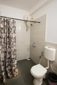 a bathroom with a toilet and a shower curtain at Red Door Hostel Anjuna in Anjuna