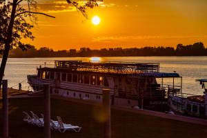 a ferry boat docked on the river at sunset at Hotel Robert's Port in Mikołajki +80 photos