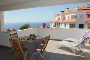 a table and chairs on a balcony with the ocean at Penthouse Quinta Village Garajau in Caniço