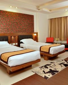 a bedroom with two beds and a red wall at Hotel Niharika in Kolkata