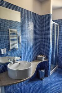 a blue tiled bathroom with a tub and a sink at Aston Hotel in Pino Torinese