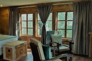 a bedroom with two chairs and a bed and windows at River Rock Lodge in Parys