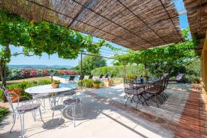 a patio with tables and chairs under a straw umbrella at La Bastide des Vignaux in Grimaud