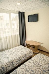a room with two beds and a table and a tv at Everena Guest House in Rokiškis