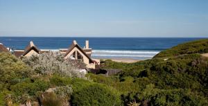 a house on a hill next to the ocean at Sandown Self-Catering in Cape St Francis