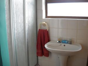 baño con lavabo blanco y toalla roja en Sandown Self-Catering, en Cape St. Francis