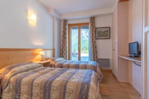 a hotel room with two beds and a television at Monte Cervino Apartment AS21 in Breuil-Cervinia