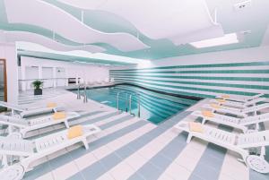 a room with a swimming pool and white chairs and a swimming pool at Terrassenhotel Reichmann in Sankt Kanzian