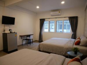 a hotel room with two beds and a couch at NP House Pratunam in Bangkok