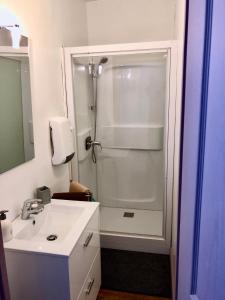 La salle de bains est pourvue d'une douche et d'un lavabo blanc. dans l'établissement L’Heure Bleue, au Crotoy