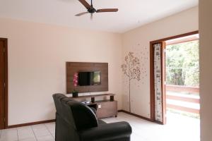 sala de estar con silla y TV en Mestre Lord Apart Hotel en Porto Seguro