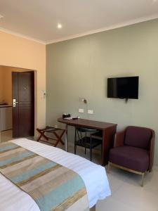 Habitación de hotel con cama, escritorio y TV. en Bannerloft Guest house, en Gaborone