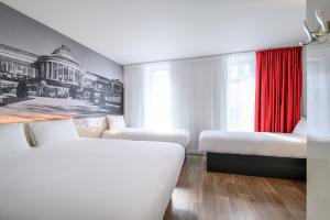 Cette chambre comprend 3 lits et un rideau rouge. dans l'établissement B&B HOTEL Brussels Centre Gare du Midi, à Bruxelles