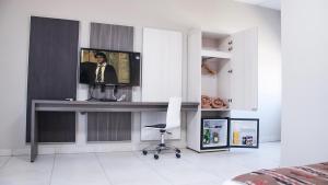 Un dormitorio con un escritorio con televisión y una silla. en Samay Hotel Boutique, en Colonia Dora