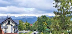 a house on a street with mountains in the background at VIP Apartamenty FOLK RESIDENCE in Zakopane
