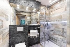 La salle de bains est pourvue d'une douche en verre et d'un lavabo. dans l'établissement Apartamenty Polana Sywarne Zakopane, à Kościelisko