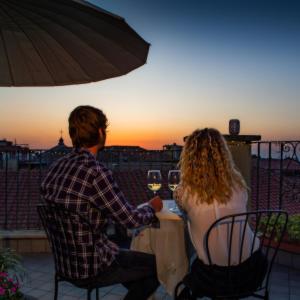 Un uomo e una donna seduti a un tavolo con bicchieri da vino di B&B Buonfiglio Cicconcelli - Terrazza panoramica a Frascati